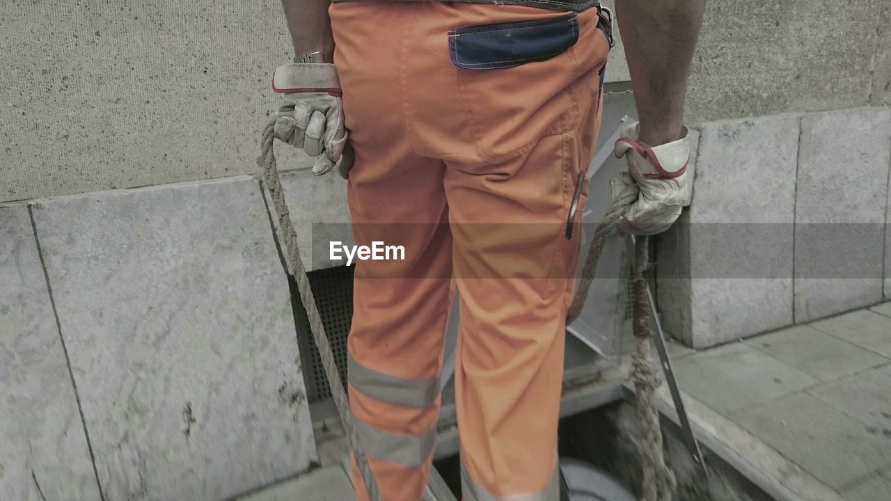 Low section of worker holding rope