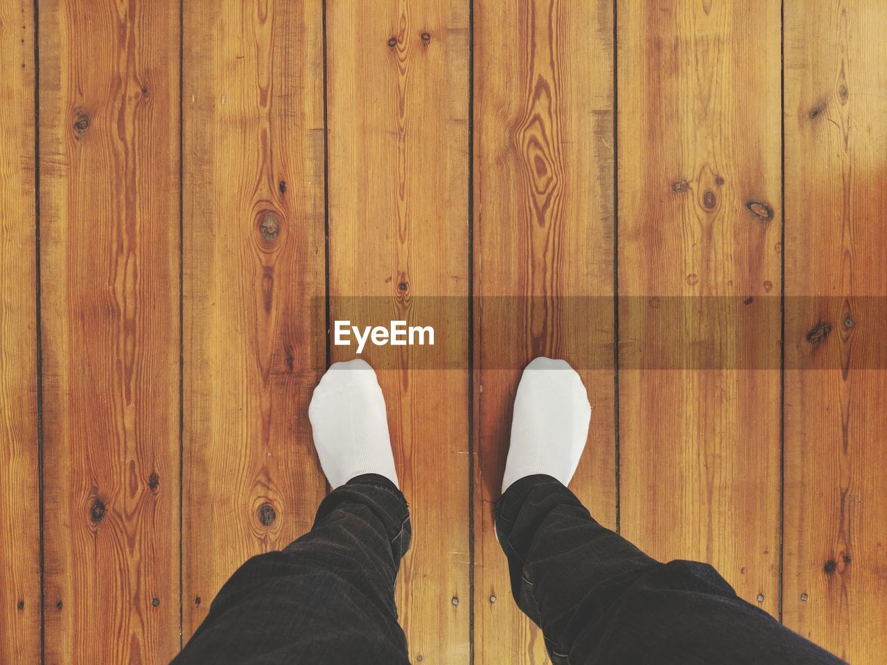 LOW SECTION OF MAN STANDING ON WOODEN FLOORING