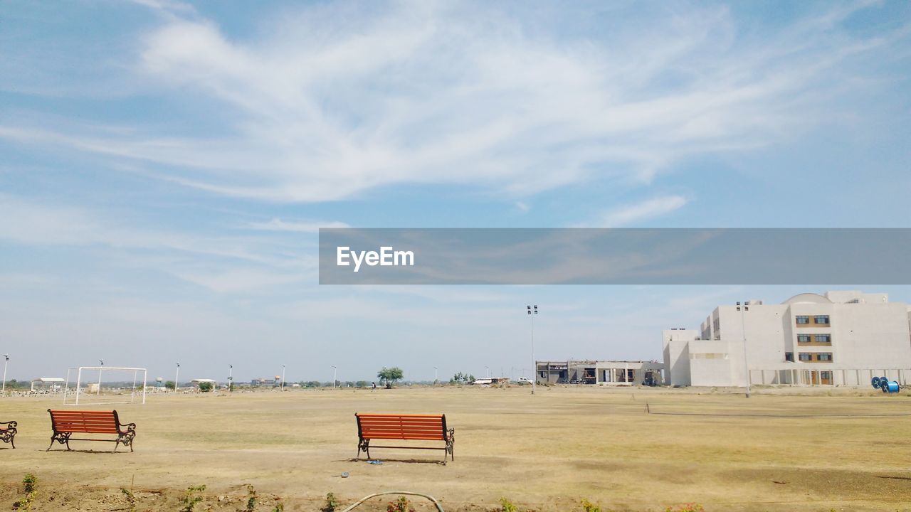 Benches on field against sky