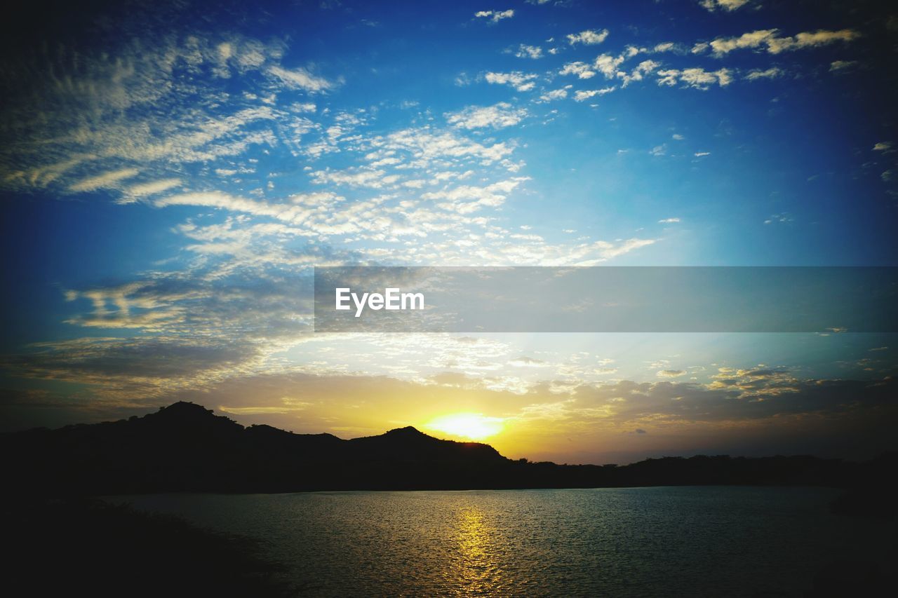 SCENIC VIEW OF LAKE BY SILHOUETTE MOUNTAINS AGAINST SKY