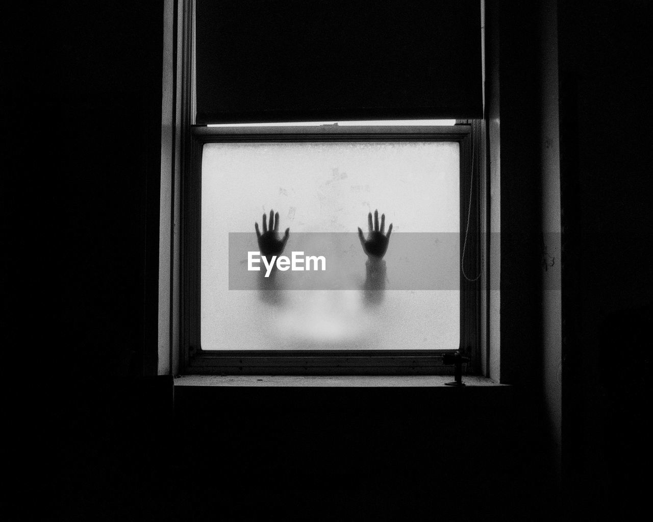 Silhouette of hands on frosted glass window