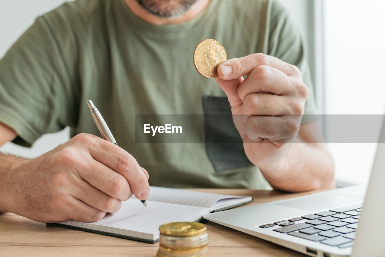 Telecommuter trading with bitcoin cryptocurrency from home office, selective focus