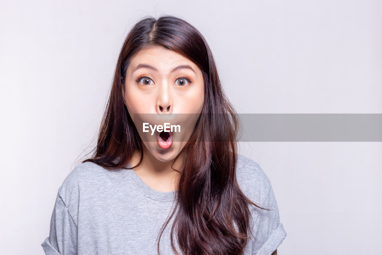 Portrait of beautiful young woman against gray background