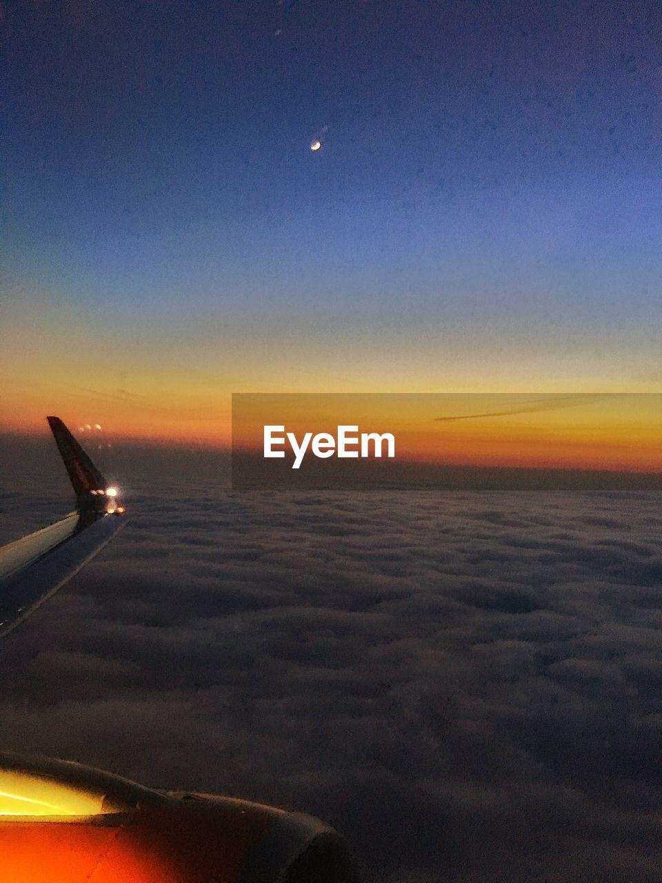 CROPPED IMAGE OF AIRPLANE WING OVER CLOUDS