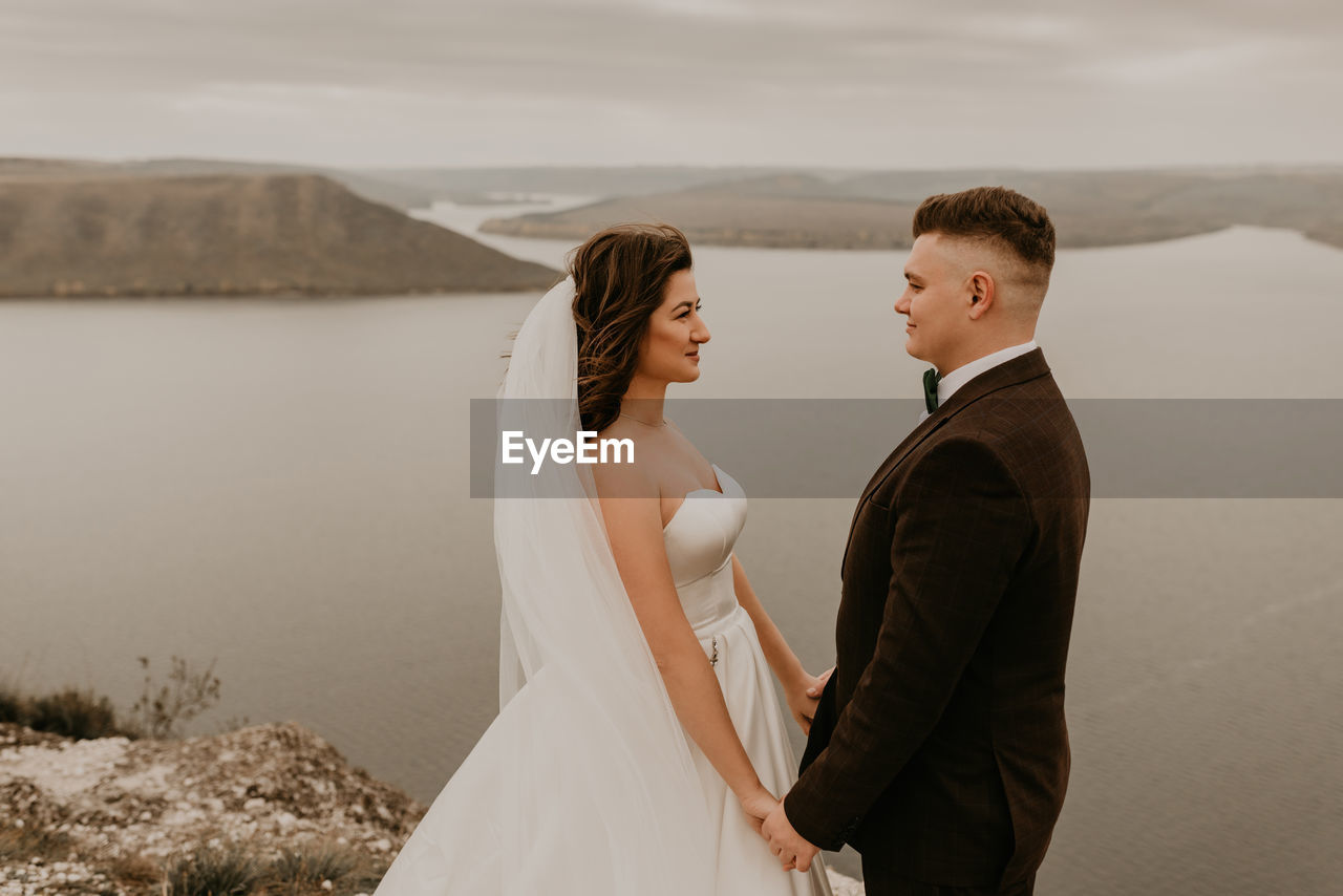 portrait of smiling couple standing against sky during sunset