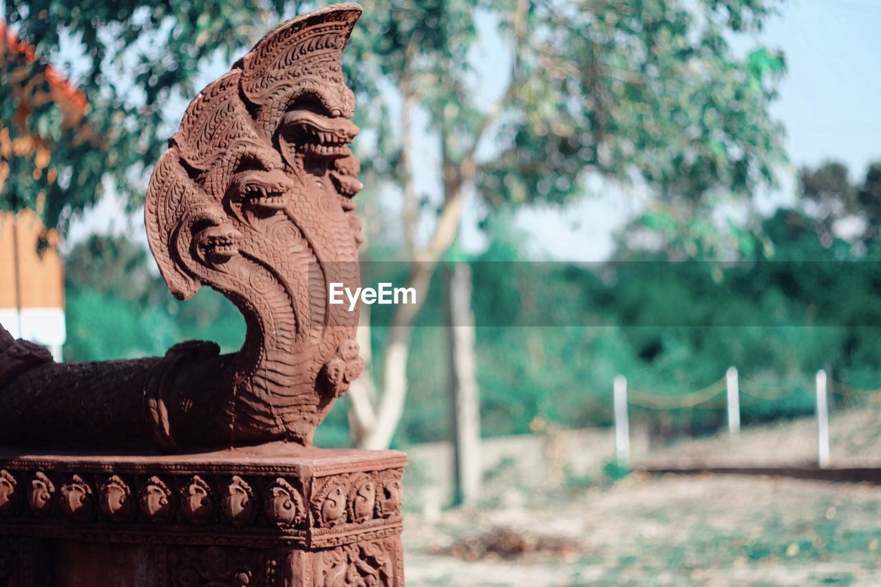 Statue against trees on field during sunny day