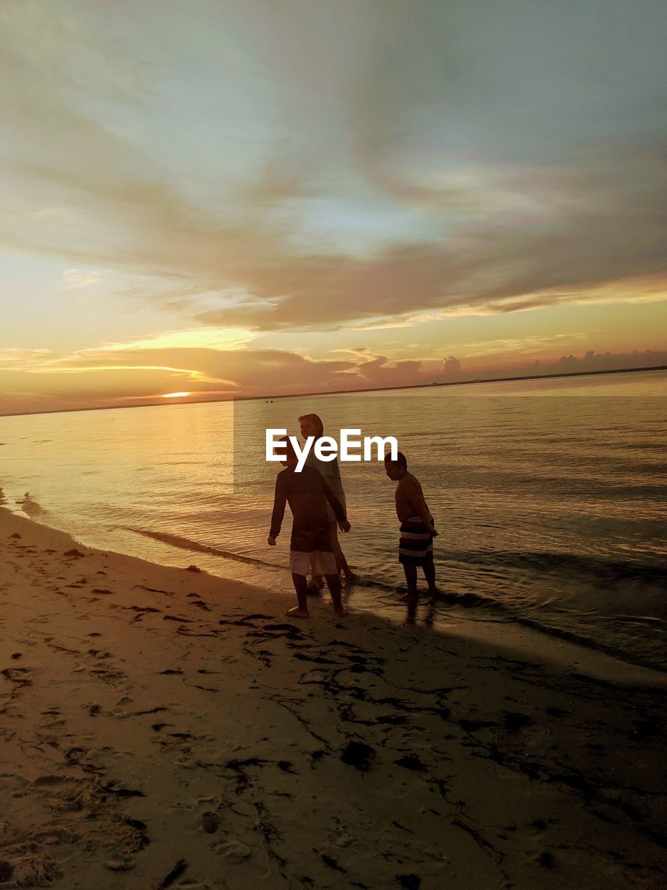 FRIENDS ON SHORE AT BEACH AGAINST SKY DURING SUNSET