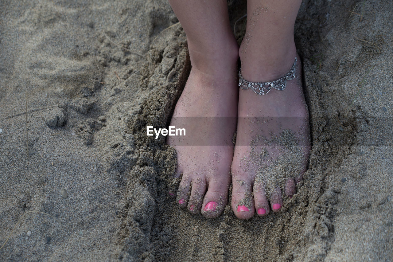 Low section of woman on sand at beach