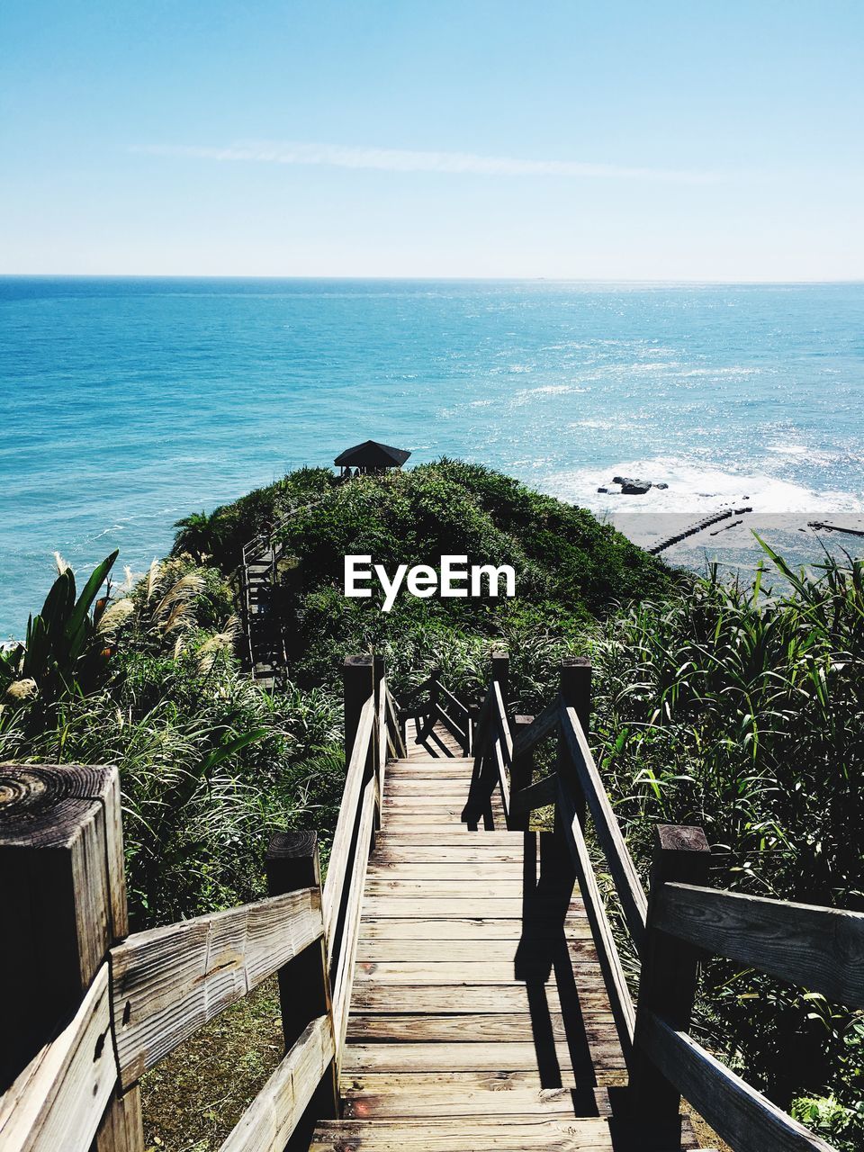 Staircase leading towards sea against sky