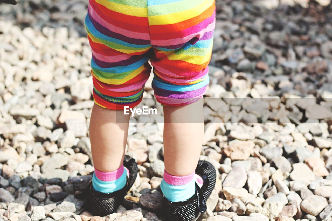 Low section of child standing on rocky field