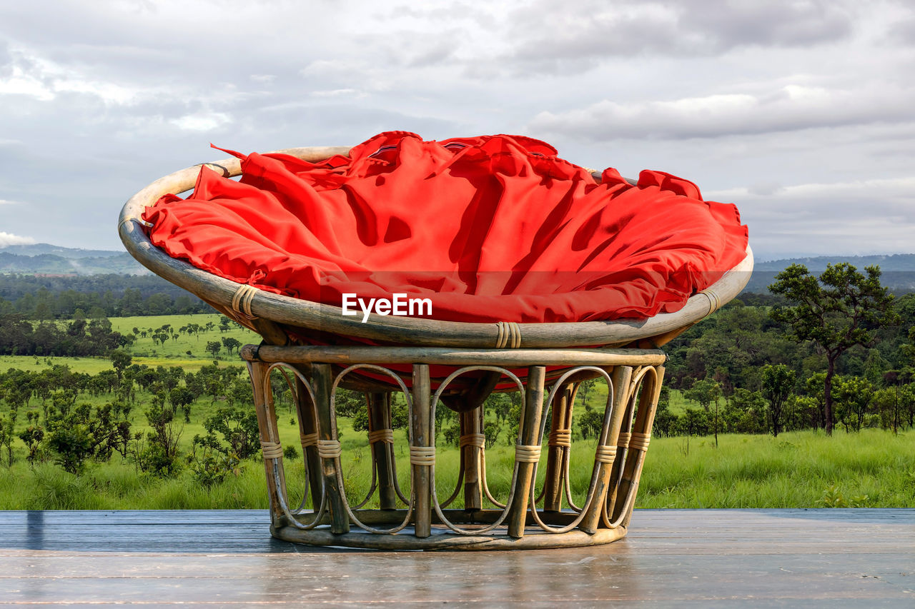 Chairs made of rattan and upholstery fabrics in red on wooden terrace .