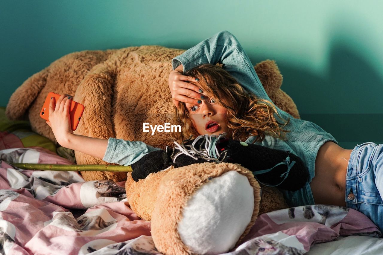 Surprised girl lying on teddy bear