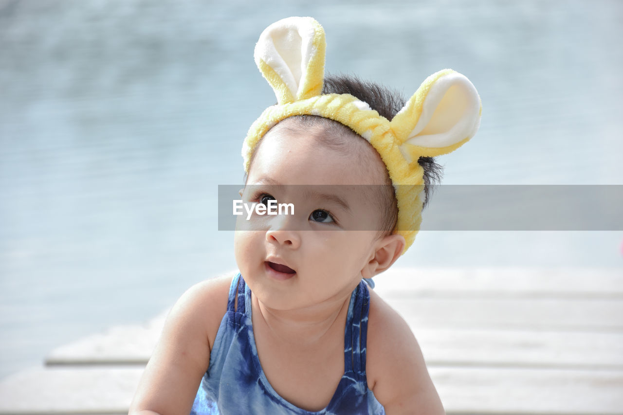 Close-up of cute baby girl wearing headband on pier in lake