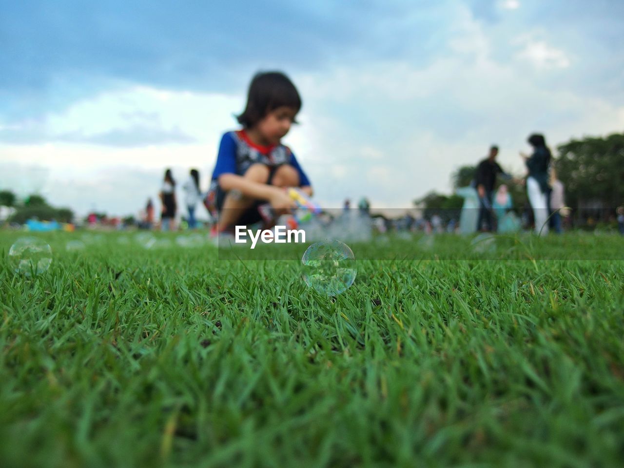 Boy playing while blowing bubbles on field