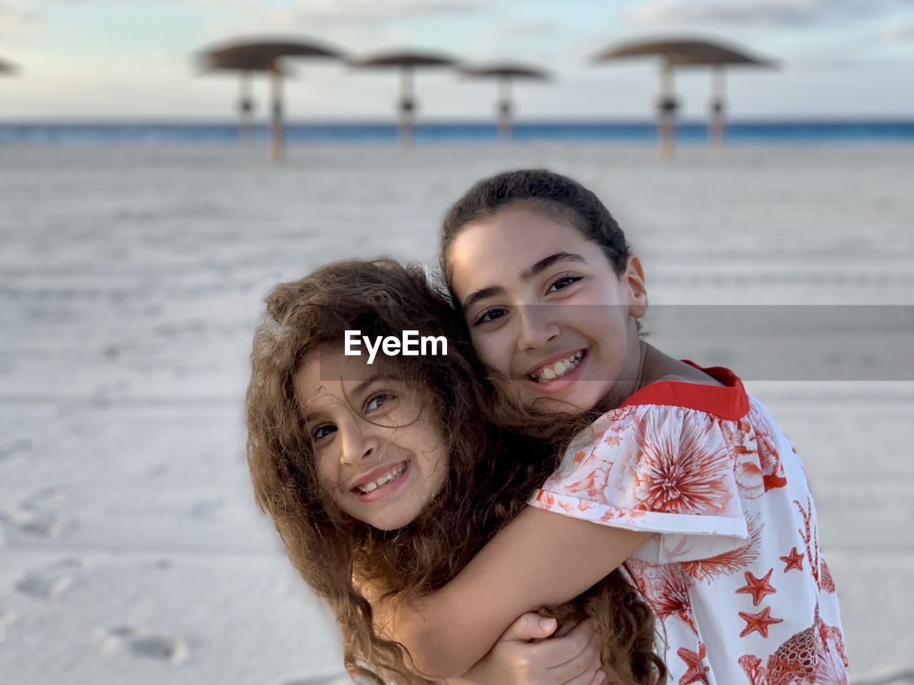 Portrait of two young girls hugging at beach. friendship sisters