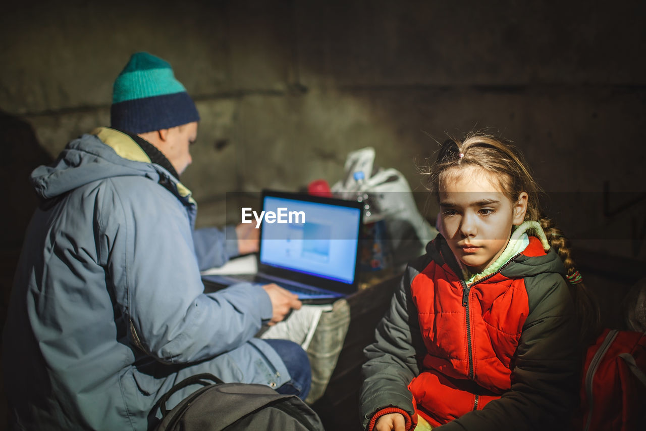 Ukrainian girl and journalist sit in bomb shelter, he works and posts news about russian invaders