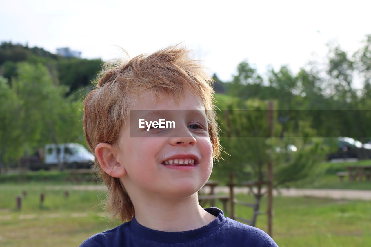 Portrait of a shaggy boy with blond hair and a sly look. joyful six year old boy.