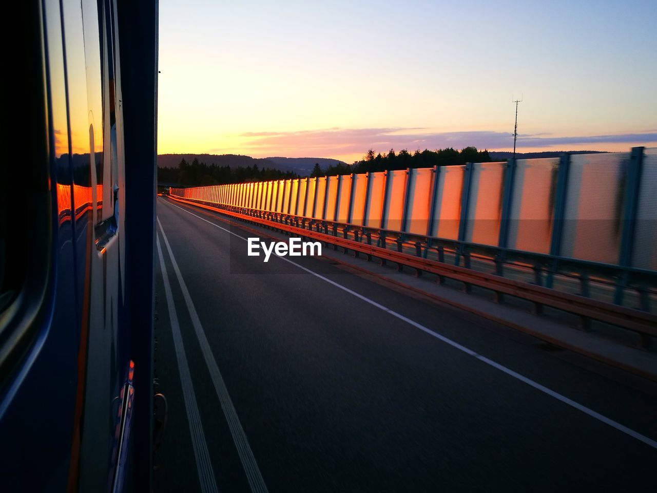 TRAIN ON ROAD AGAINST SKY AT SUNSET