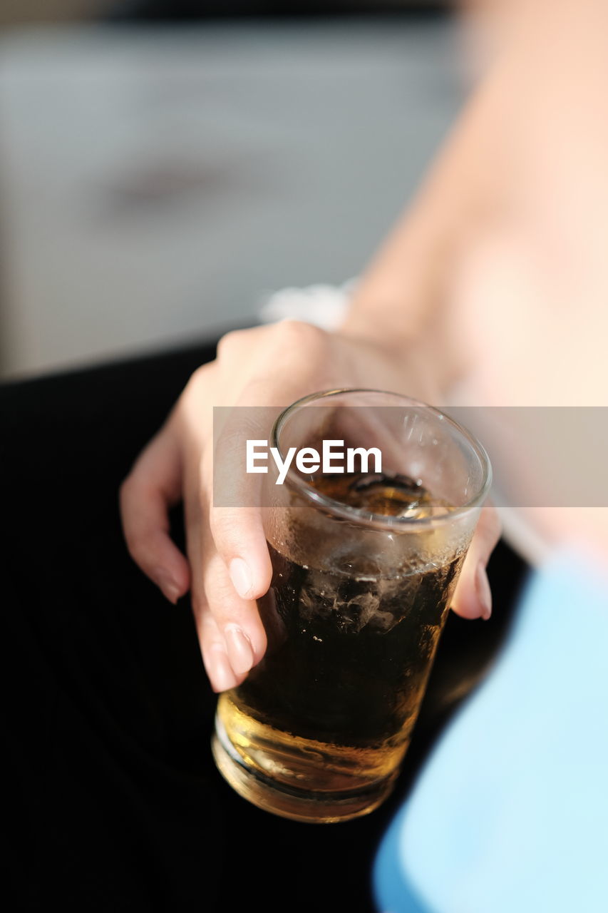 Cropped hand of person holding drink in glass