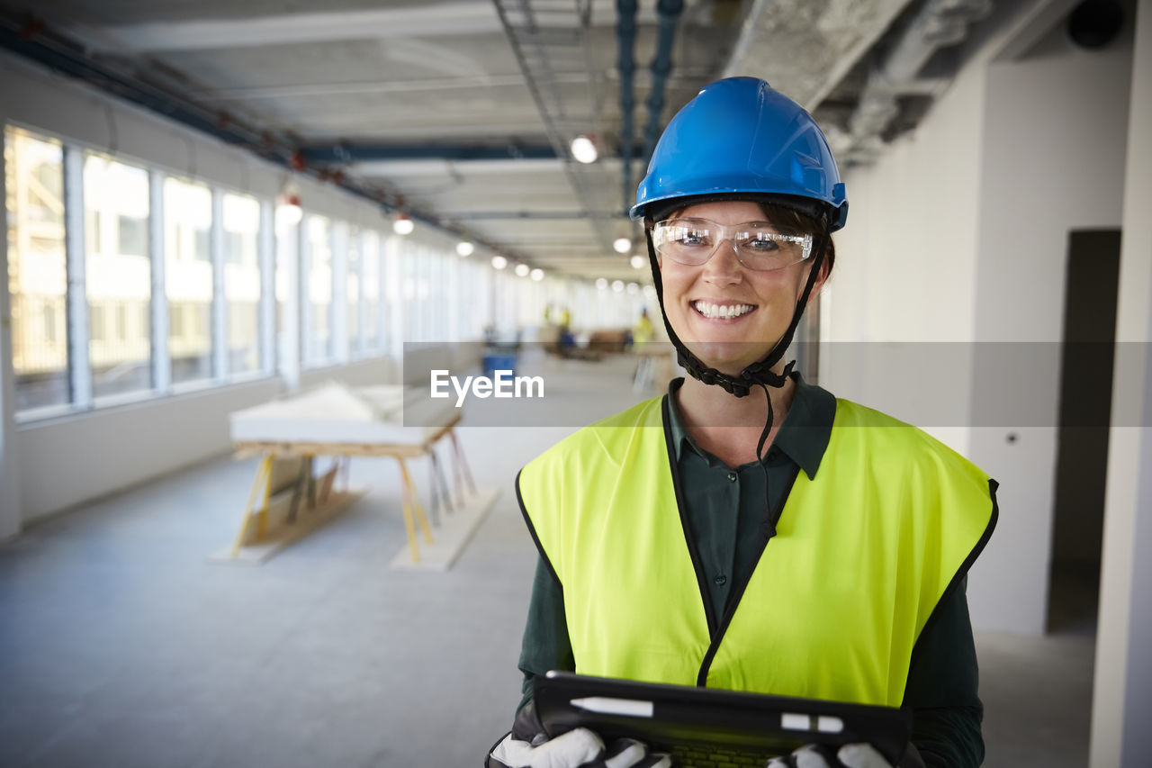 Portrait of smiling female engineer in protective workwear at construction site