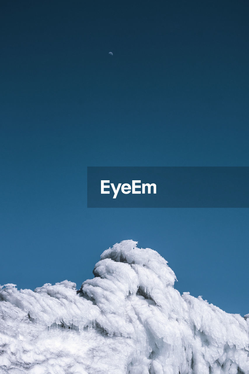 LOW ANGLE VIEW OF SNOWCAPPED MOUNTAINS AGAINST BLUE SKY