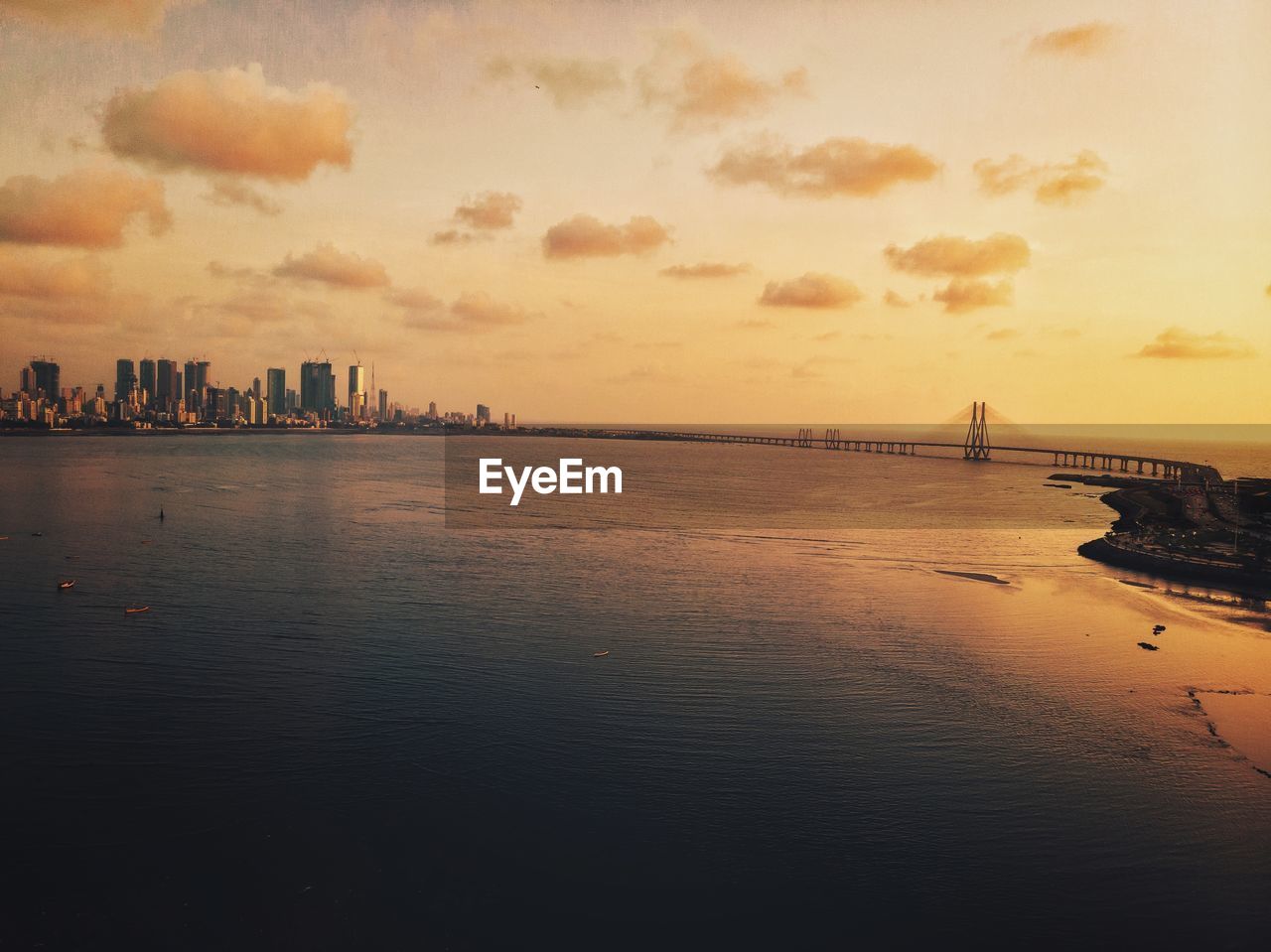 Mumbai city scenic view of sea by buildings against sky during sunset