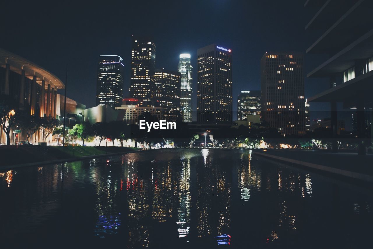 Canal against illuminated cityscape against sky at night