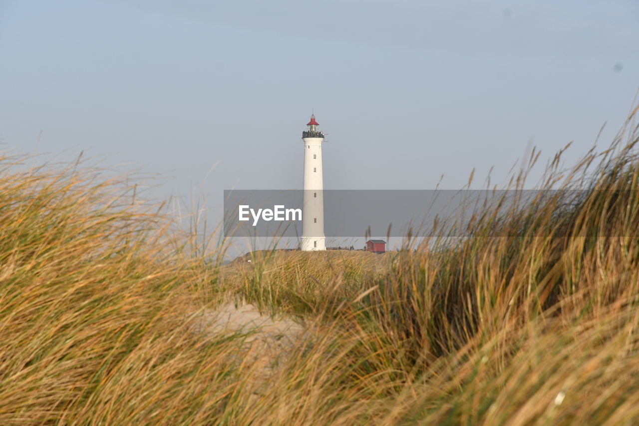 Lighthouse on beach against sky