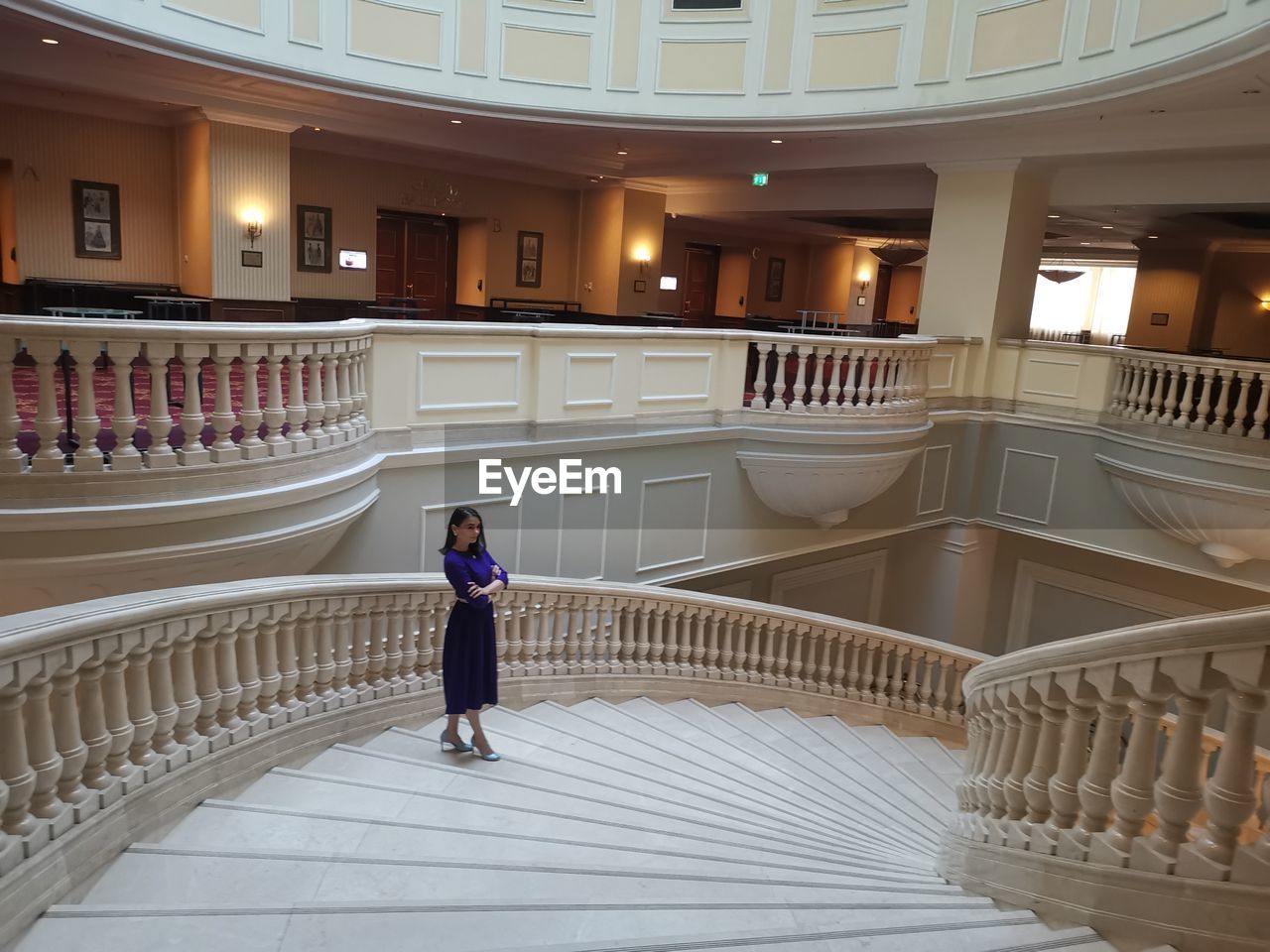 FULL LENGTH OF WOMAN STANDING BY RAILING AGAINST BUILDING