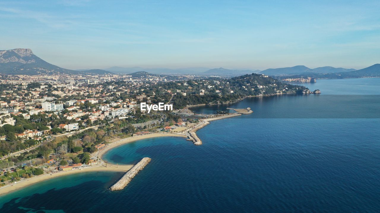 water, architecture, sea, city, coast, building exterior, nature, sky, built structure, land, travel destinations, aerial photography, building, mountain, aerial view, beach, travel, scenics - nature, cityscape, blue, high angle view, horizon, bay, transportation, coastline, landscape, no people, body of water, beauty in nature, environment, outdoors, day, tourism, residential district, holiday, vacation, nautical vessel, house, trip, town, bay of water, shore, harbor, cloud, ocean, mode of transportation