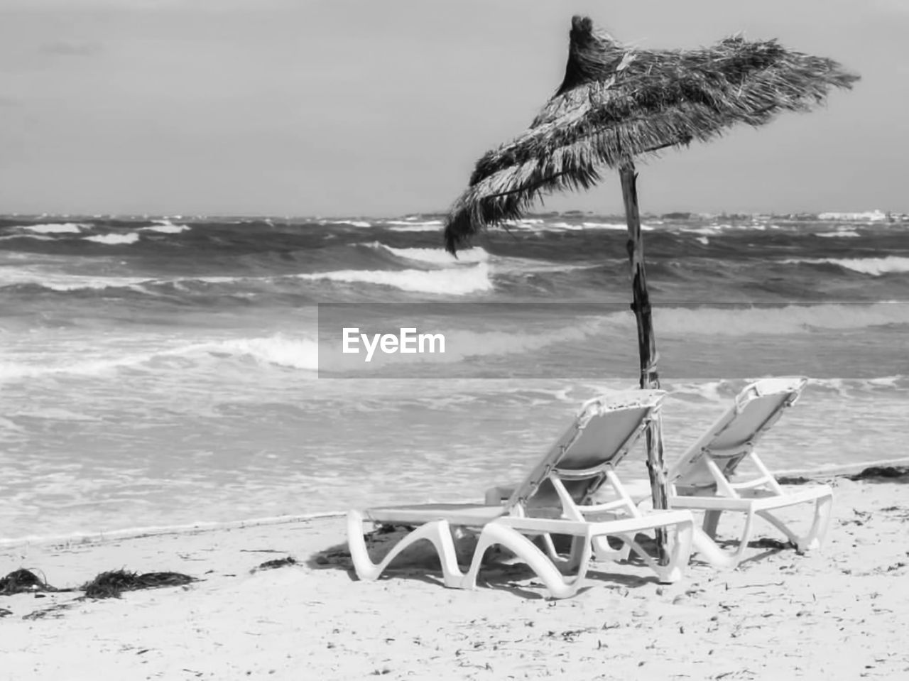 Deck chairs on beach against sky