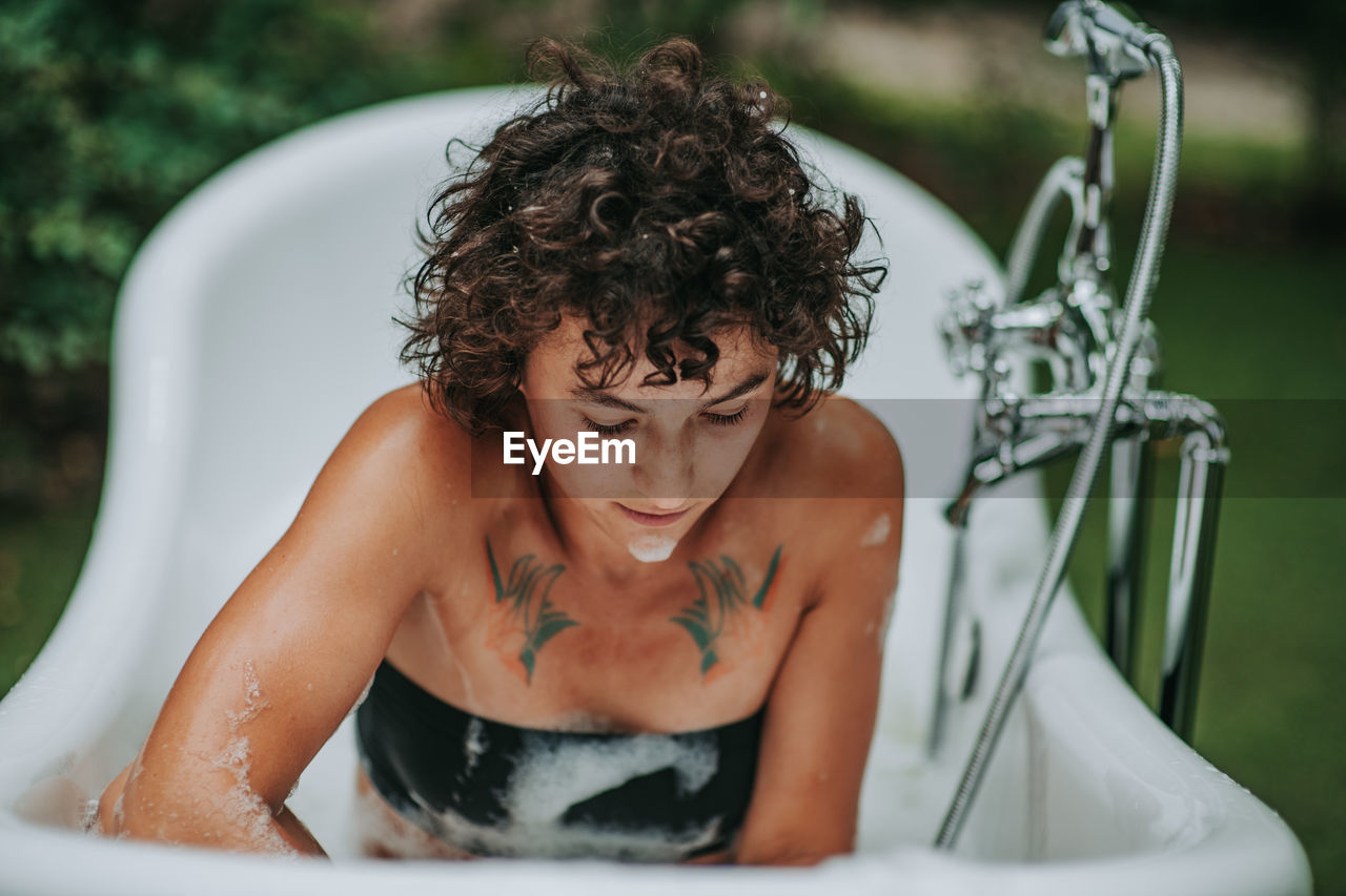 Young woman sitting in bathtub outdoors