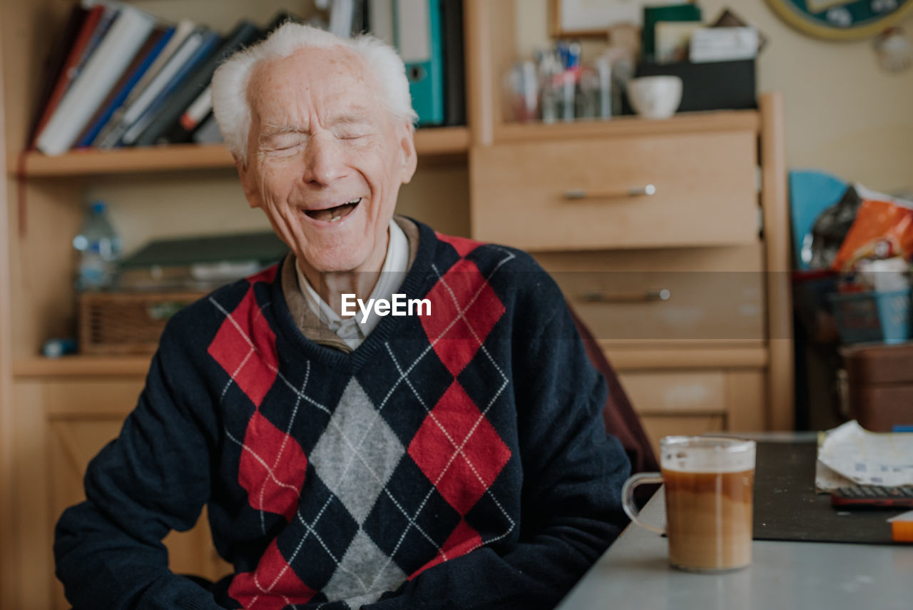 Smiling senior man with coffee cup on table at home