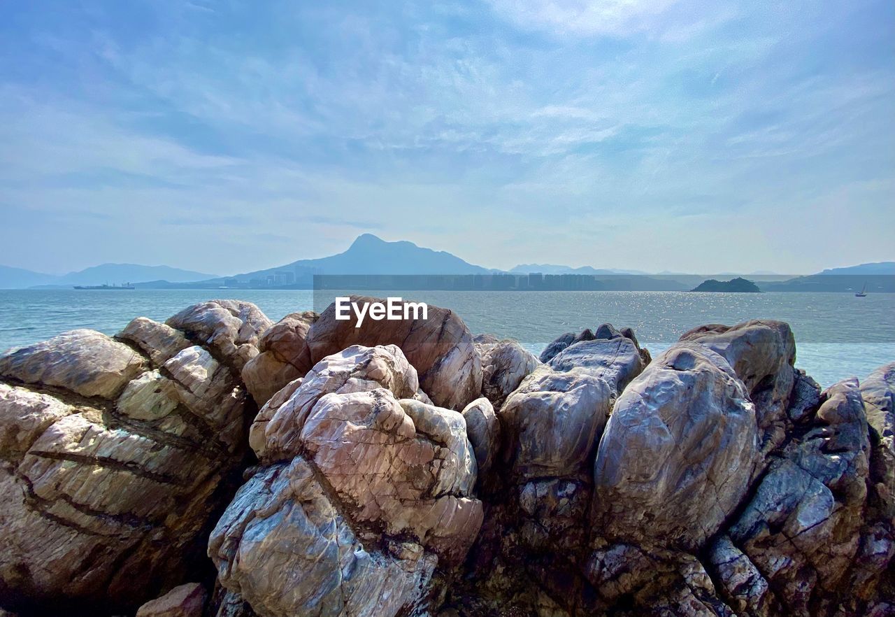 rock, sea, water, sky, nature, shore, land, beach, scenics - nature, coast, beauty in nature, cloud, no people, tranquility, ocean, landscape, environment, travel destinations, tranquil scene, day, coastline, outdoors, travel, body of water, blue, mountain, non-urban scene, animal wildlife