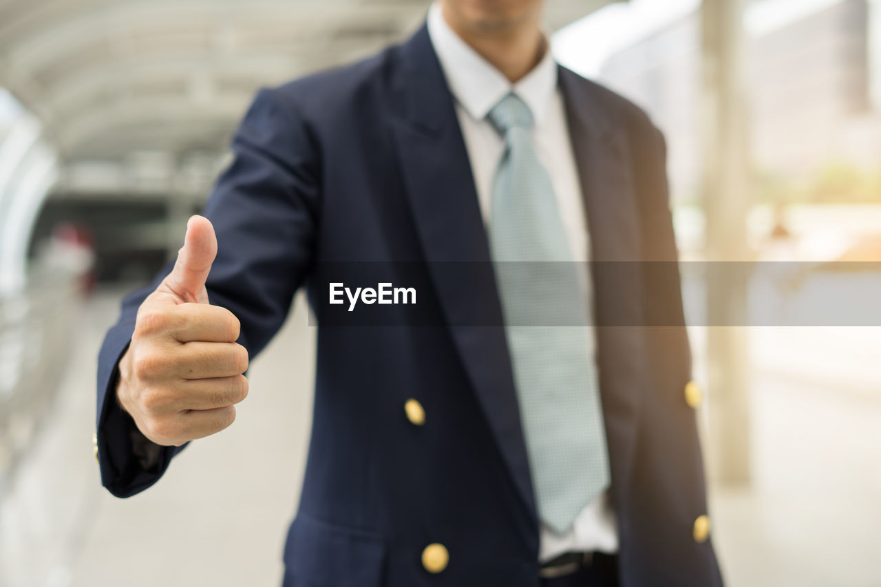 Midsection of businessman gesturing at office