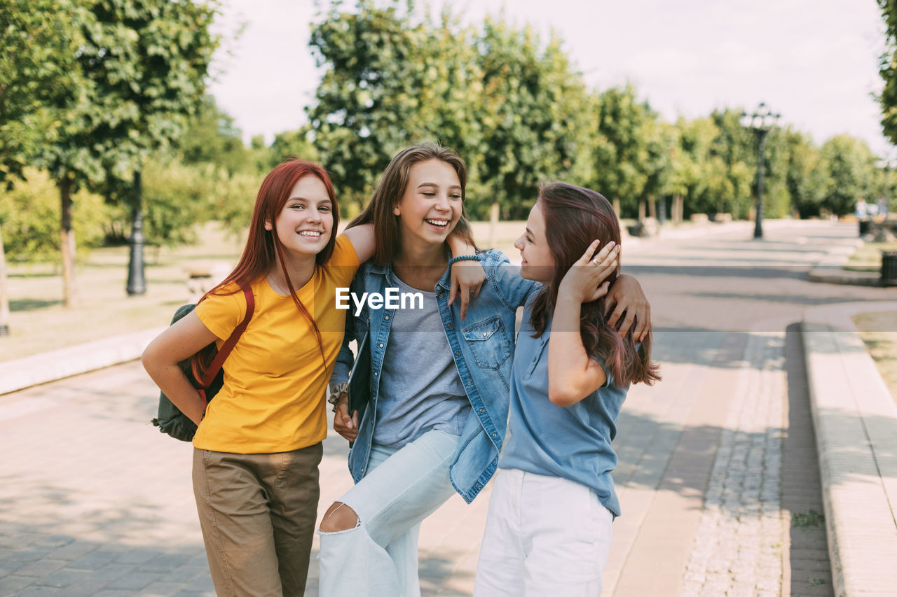 Three cheerful teenage girls schoolgirls coming from school. the concept of training and education