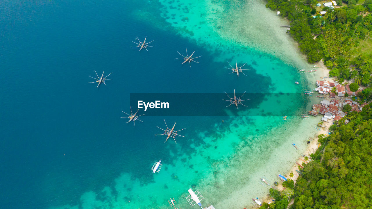 Aerial view of village of fishermen with houses on the water, with fishing boats, samal island. 