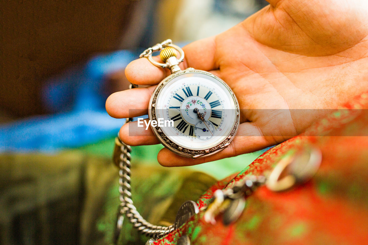 Cropped hand holding pocket watch