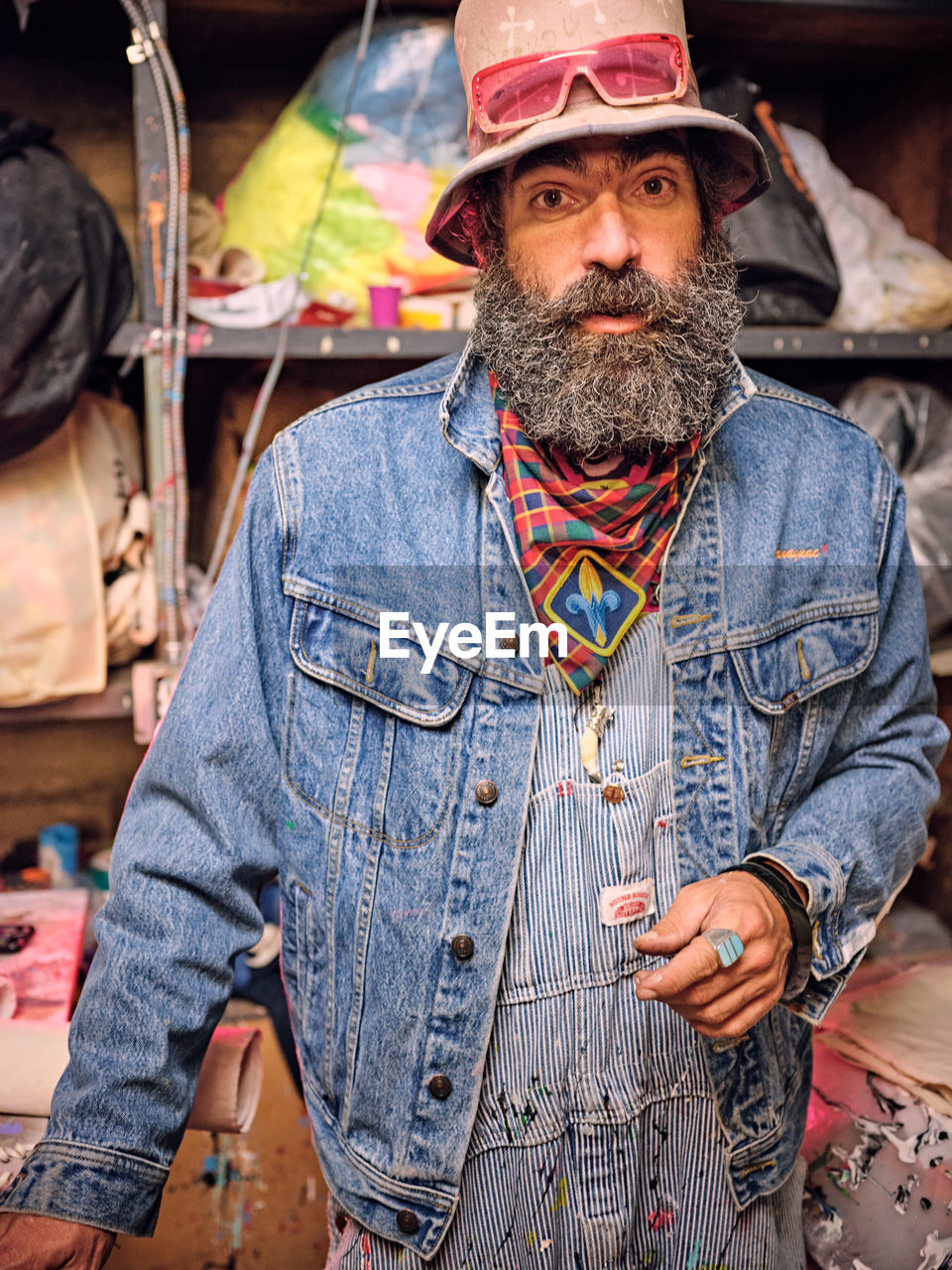 Portrait of eclectically dressed artist in his art making space.