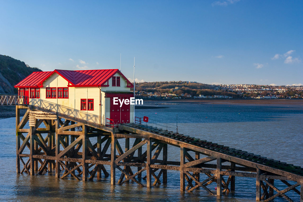 Stilt houses by sea against sky