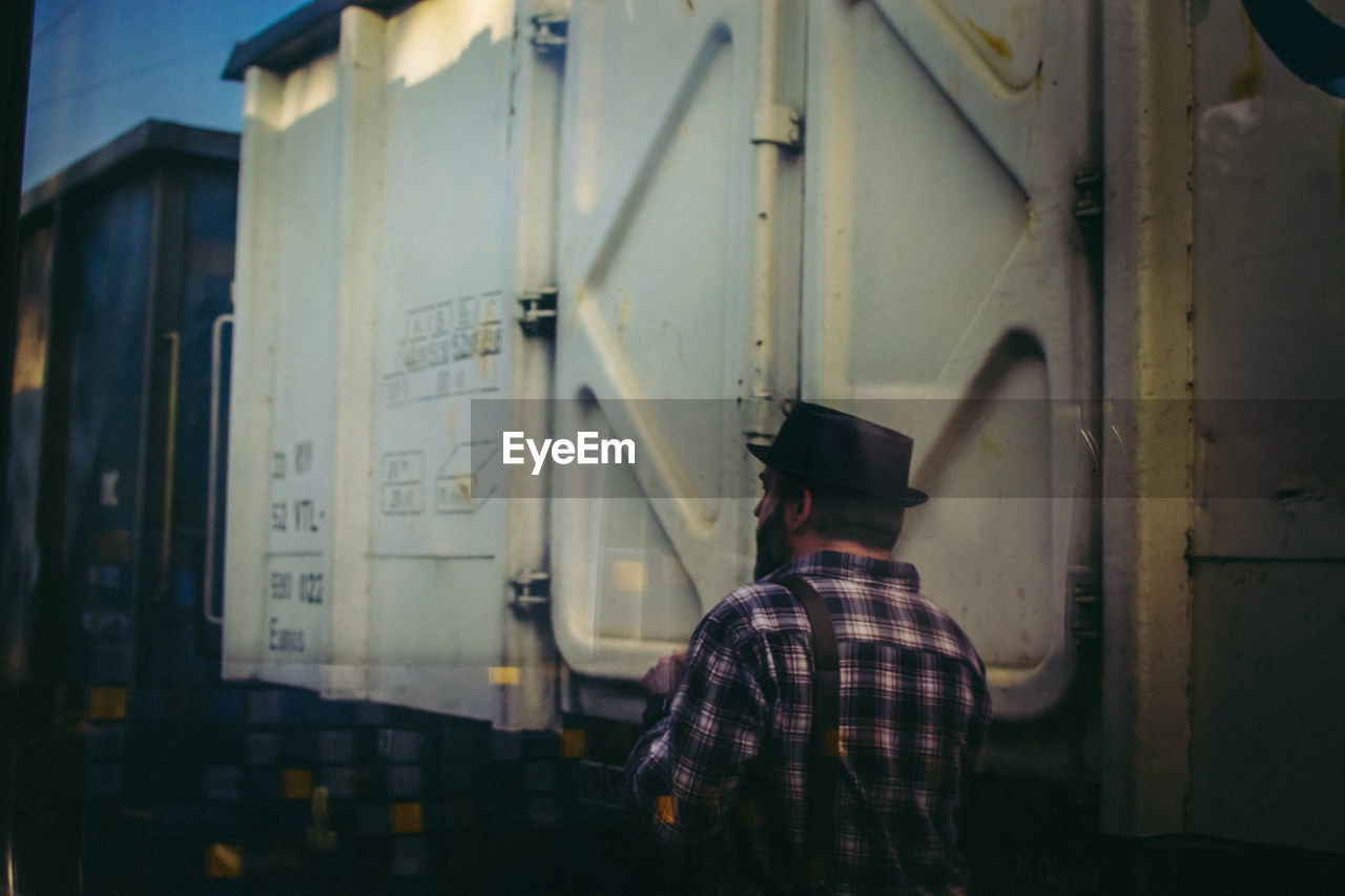 REAR VIEW OF MAN STANDING AGAINST TRAIN