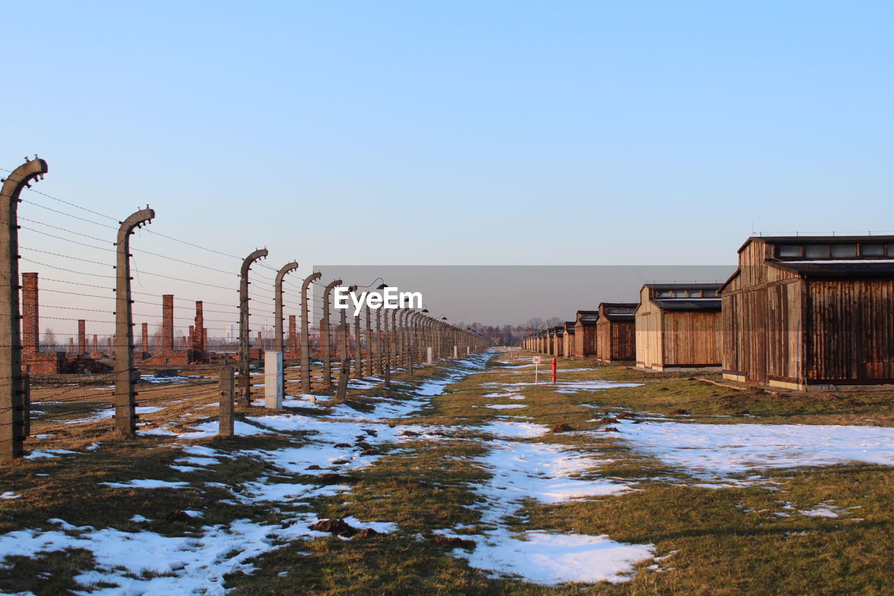 WOODEN POSTS ON SNOW FIELD AGAINST CLEAR SKY