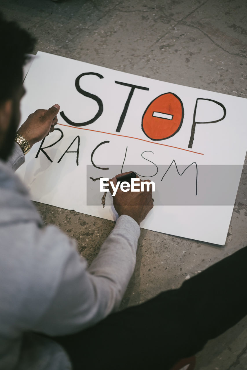 High angle view of man making signboard of racism in building