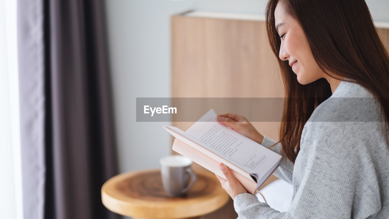 Smiling woman reading book at home