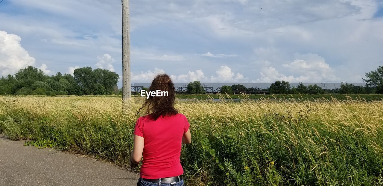 Rear view of woman standing on field against sky