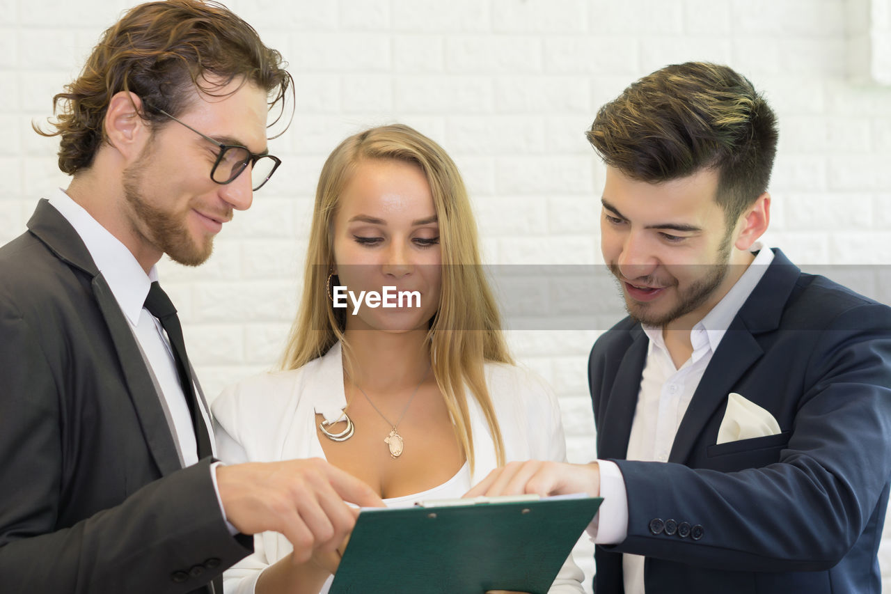 Business colleagues discussing over document while standing in office