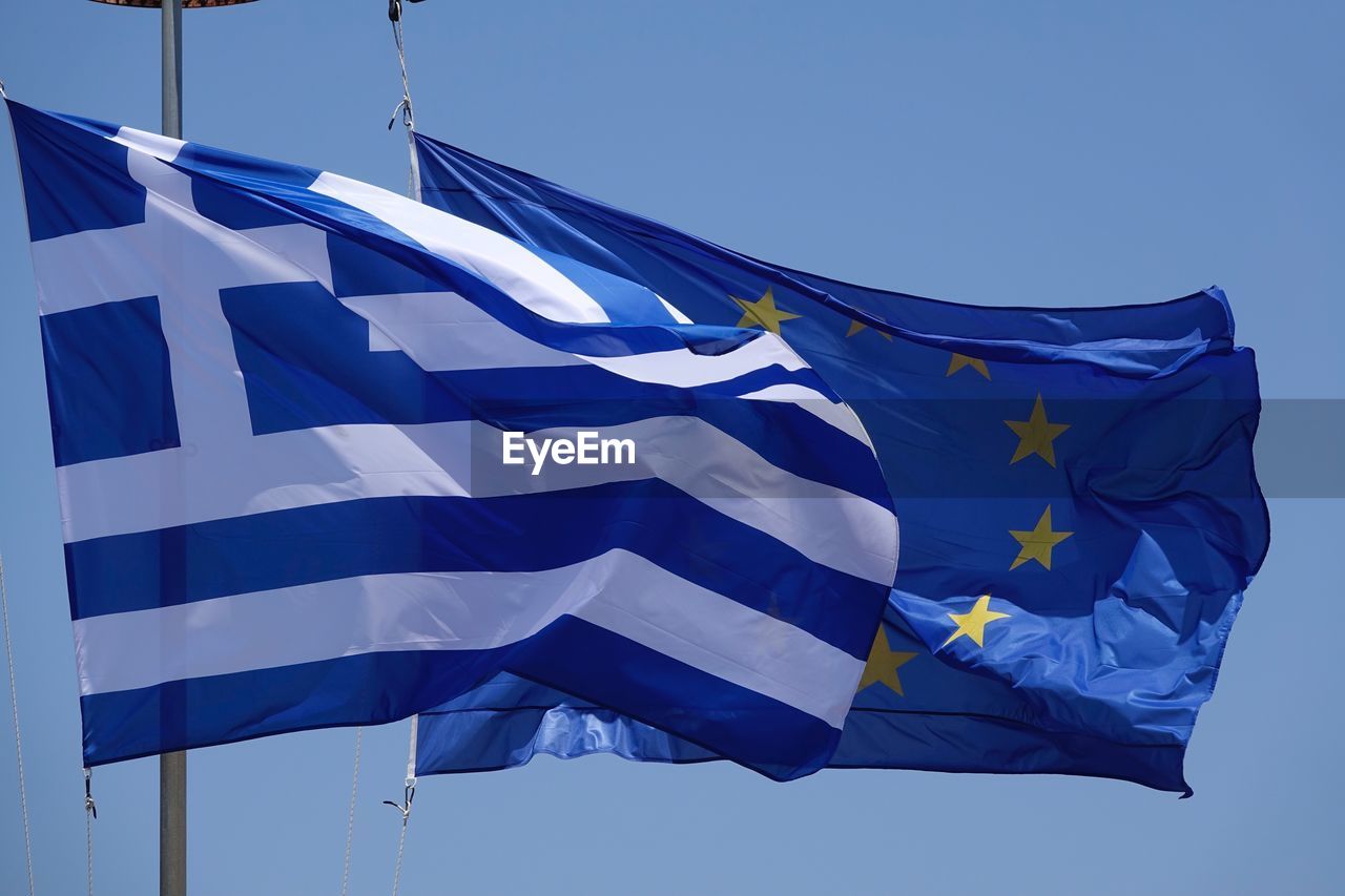 Low angle view of flags against clear blue sky