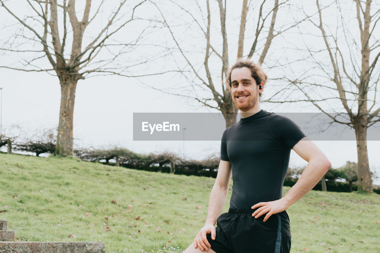 Portrait of man standing against bare tree outdoors