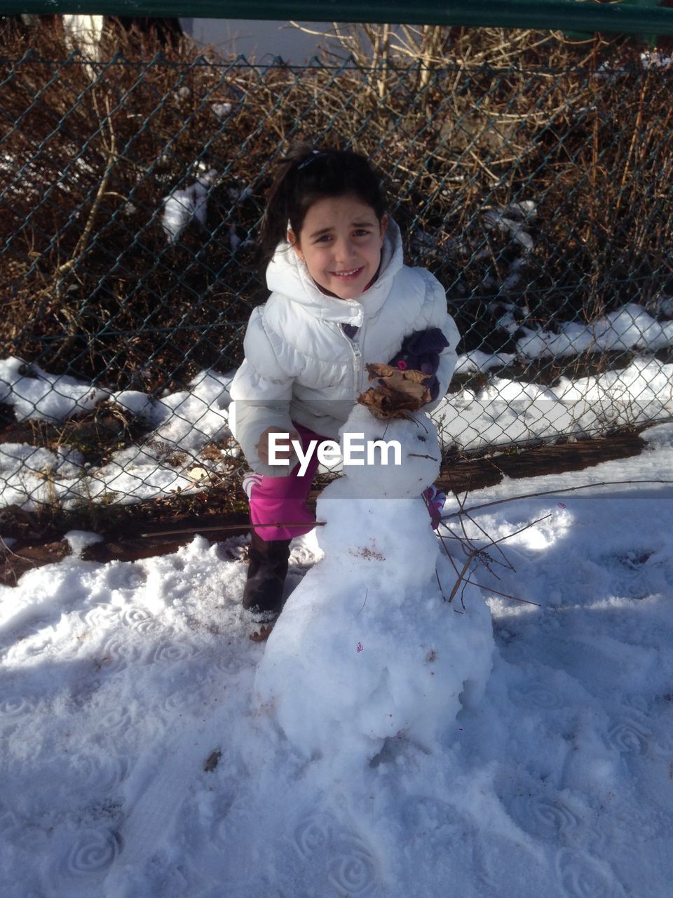 Portrait of cute girl making snowman during winter