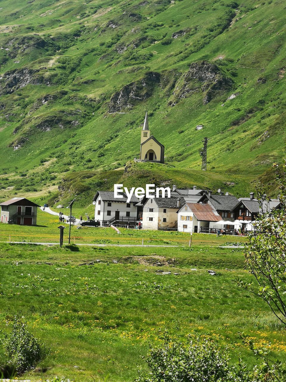 HOUSE ON FIELD BY HOUSES AGAINST MOUNTAIN